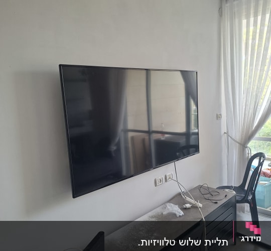 טלוויזיה מותקנת על קיר עם כבלים וציוד
